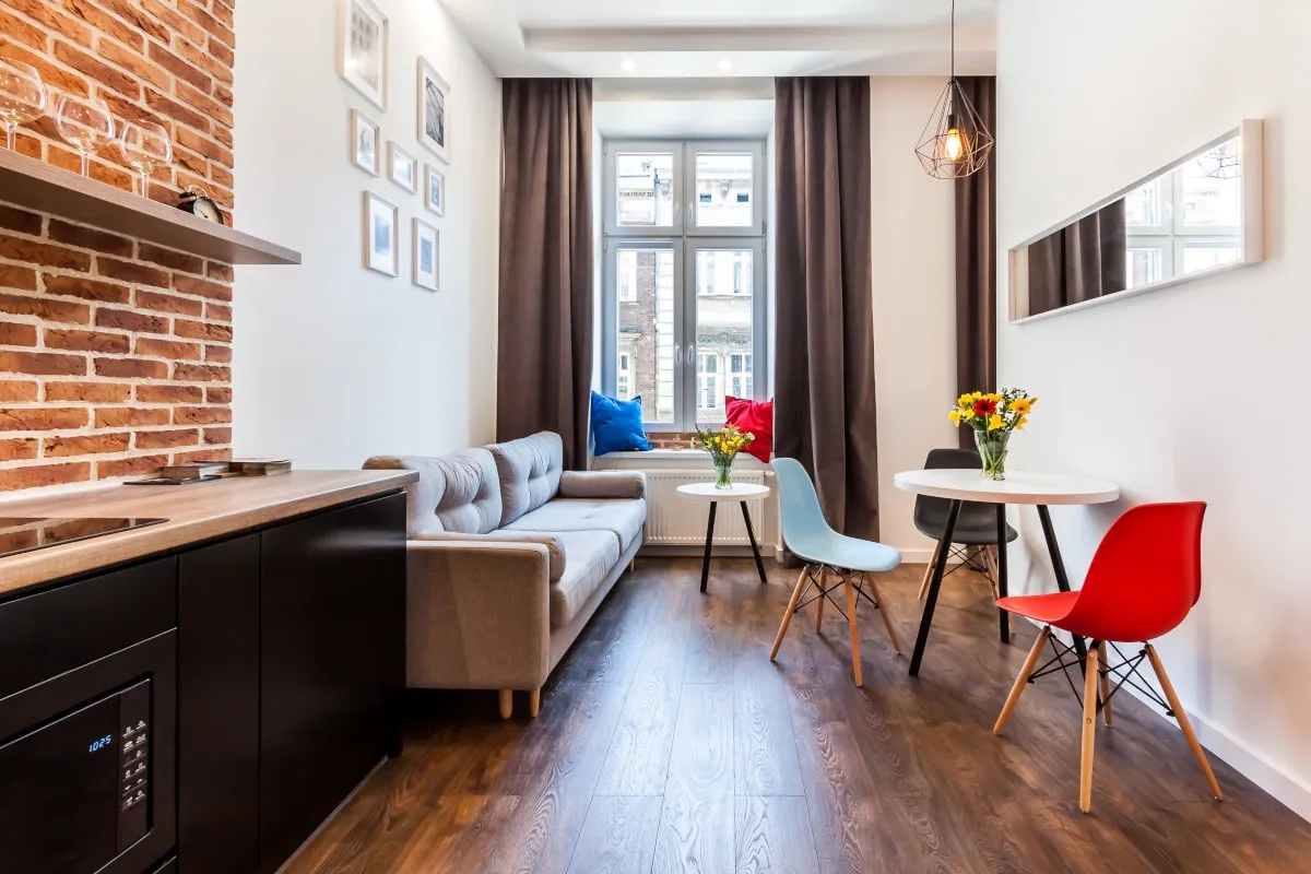 Salon apartamentu z cegłą i czerwonymi krzesłami